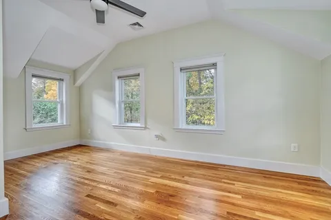 a view of an empty room with window and wooden floor