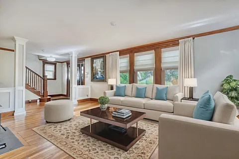 a living room with furniture a rug a lamp and a large window