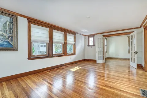 a view of an empty room with window and wooden floor