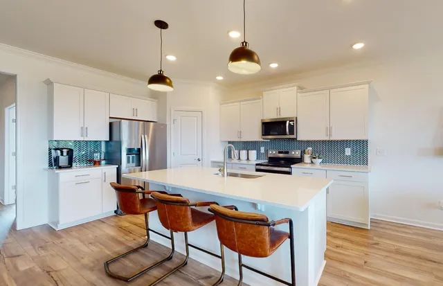 a kitchen with stainless steel appliances a stove a refrigerator a sink and a refrigerator with wooden floor