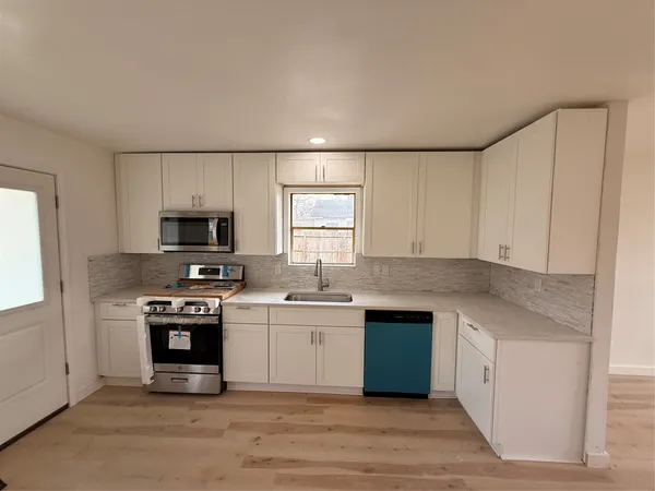 a kitchen with stainless steel appliances granite countertop a stove a sink and a refrigerator