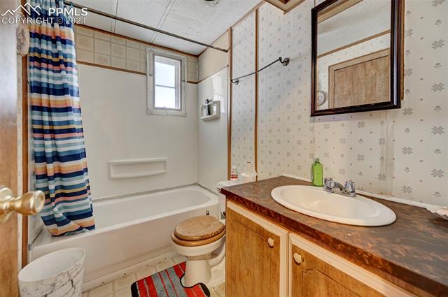 11955 Smith Road Peyton, CO 80831 - Photo 19 of 24 Full bathroom featuring vanity, toilet, and shower / bath combination with curtain