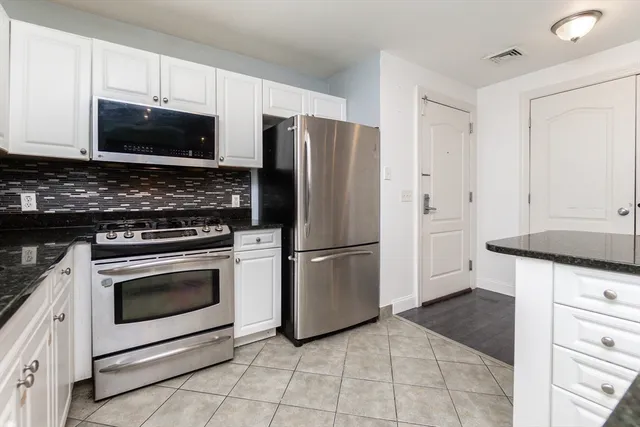 a kitchen with granite countertop a stove microwave and refrigerator