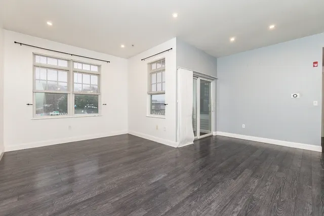 a view of an empty room with wooden floor and windows