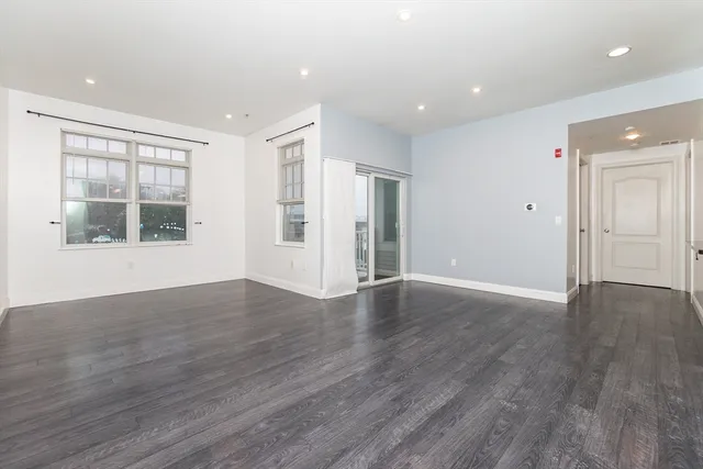 a view of an empty room with wooden floor and windows
