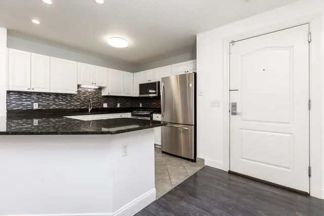 a kitchen with stainless steel appliances granite countertop a refrigerator sink and white cabinets