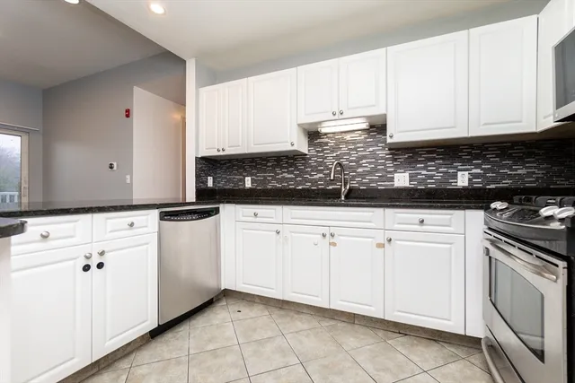 a kitchen with white cabinets granite counter tops and a stove