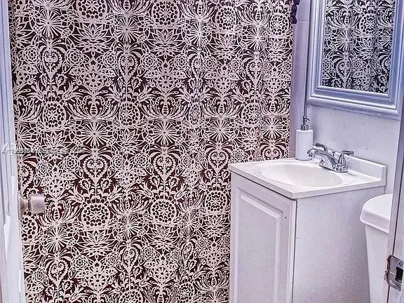 a bathroom with a sink and mirror with toilet