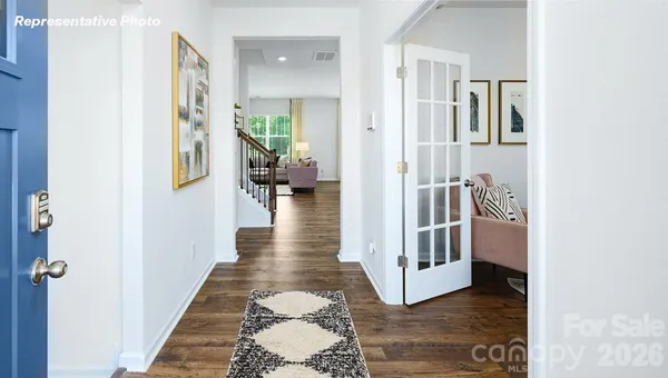 a view of a hallway with wooden floor and a living room