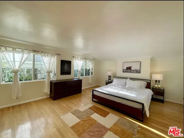 a spacious bedroom with a bed and wooden floor