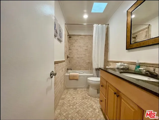 a bathroom with a granite countertop sink a toilet a mirror and shower