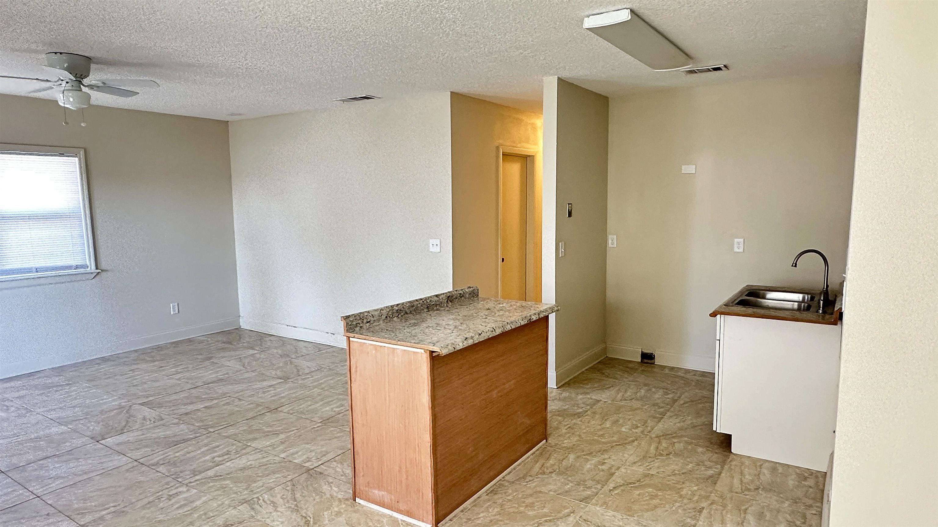 2 11th Street St. Augustine Beach, FL 32080 - Photo 14 of 72 Kitchen with a textured ceiling, a ceiling fan, a textured wall, a kitchen island, and wood finish cabinets