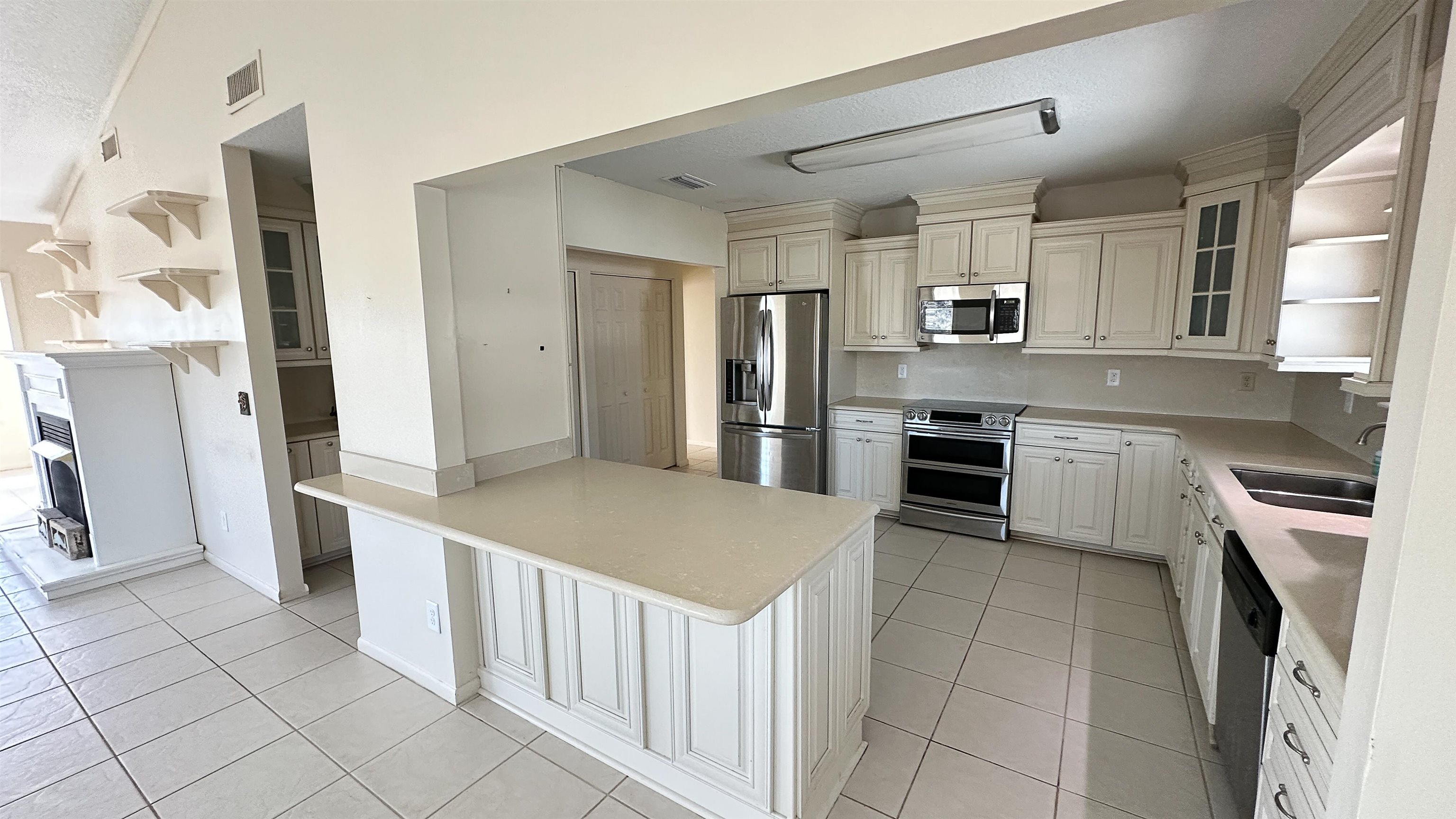 2 11th Street St. Augustine Beach, FL 32080 - Photo 51 of 72 Kitchen with open shelves, glass insert cabinets, light countertops, stainless steel appliances, and light tile patterned floors