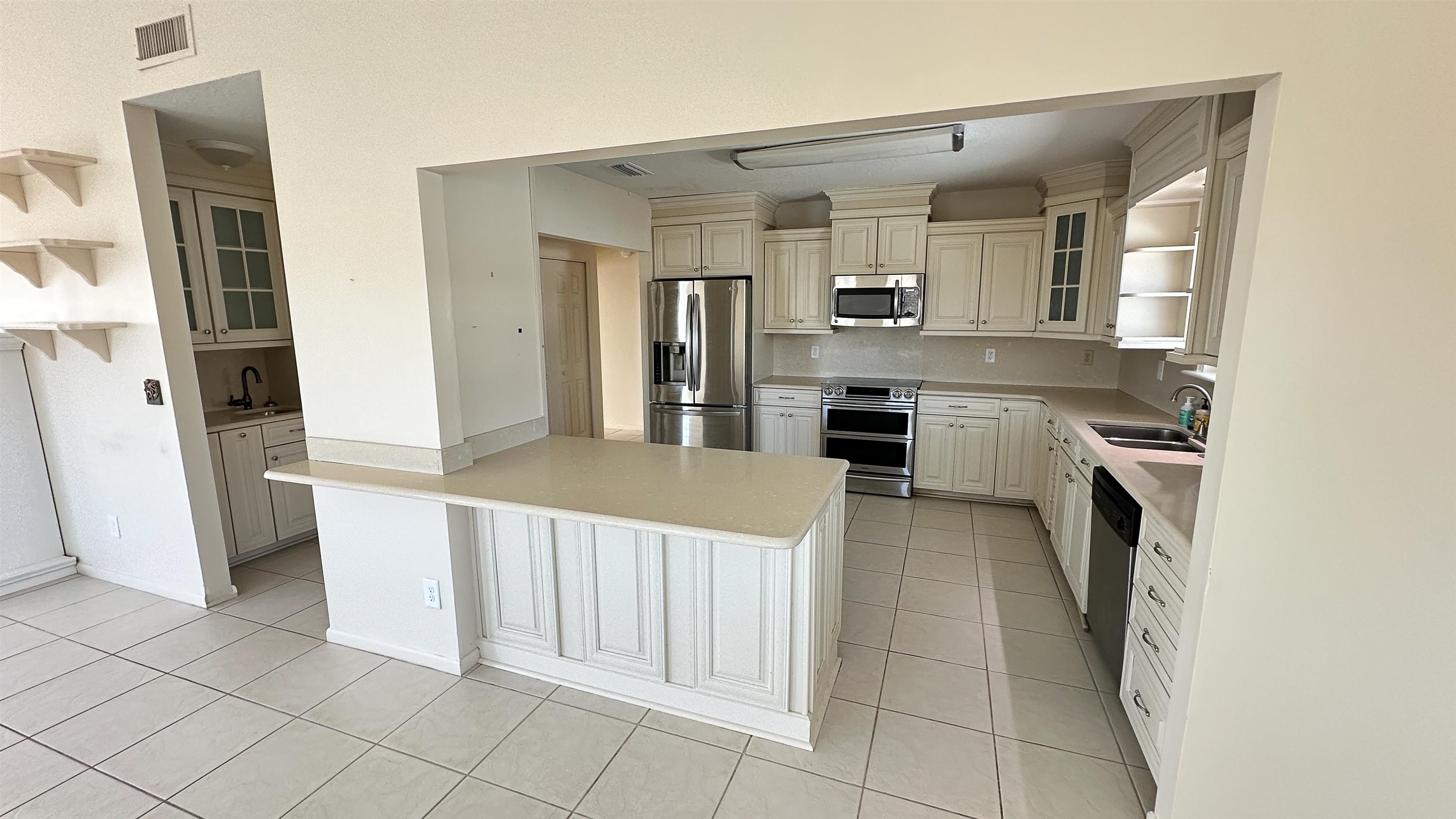 2 11th Street St. Augustine Beach, FL 32080 - Photo 52 of 72 Kitchen with glass insert cabinets, open shelves, stainless steel appliances, light tile patterned flooring, and a peninsula