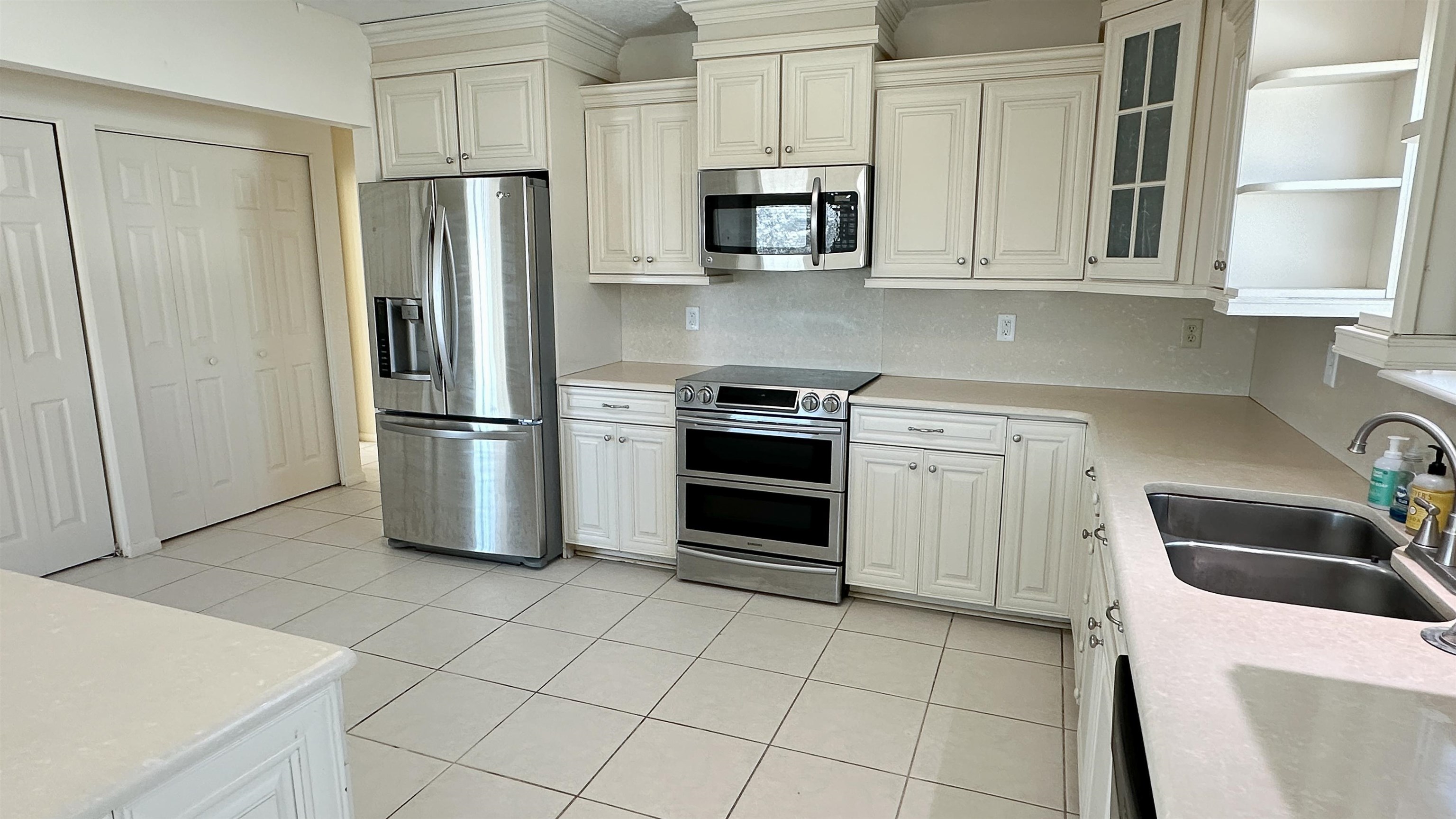 2 11th Street St. Augustine Beach, FL 32080 - Photo 54 of 72 Kitchen featuring stainless steel appliances, glass fronted cabinets, white cabinets, and light tile patterned flooring