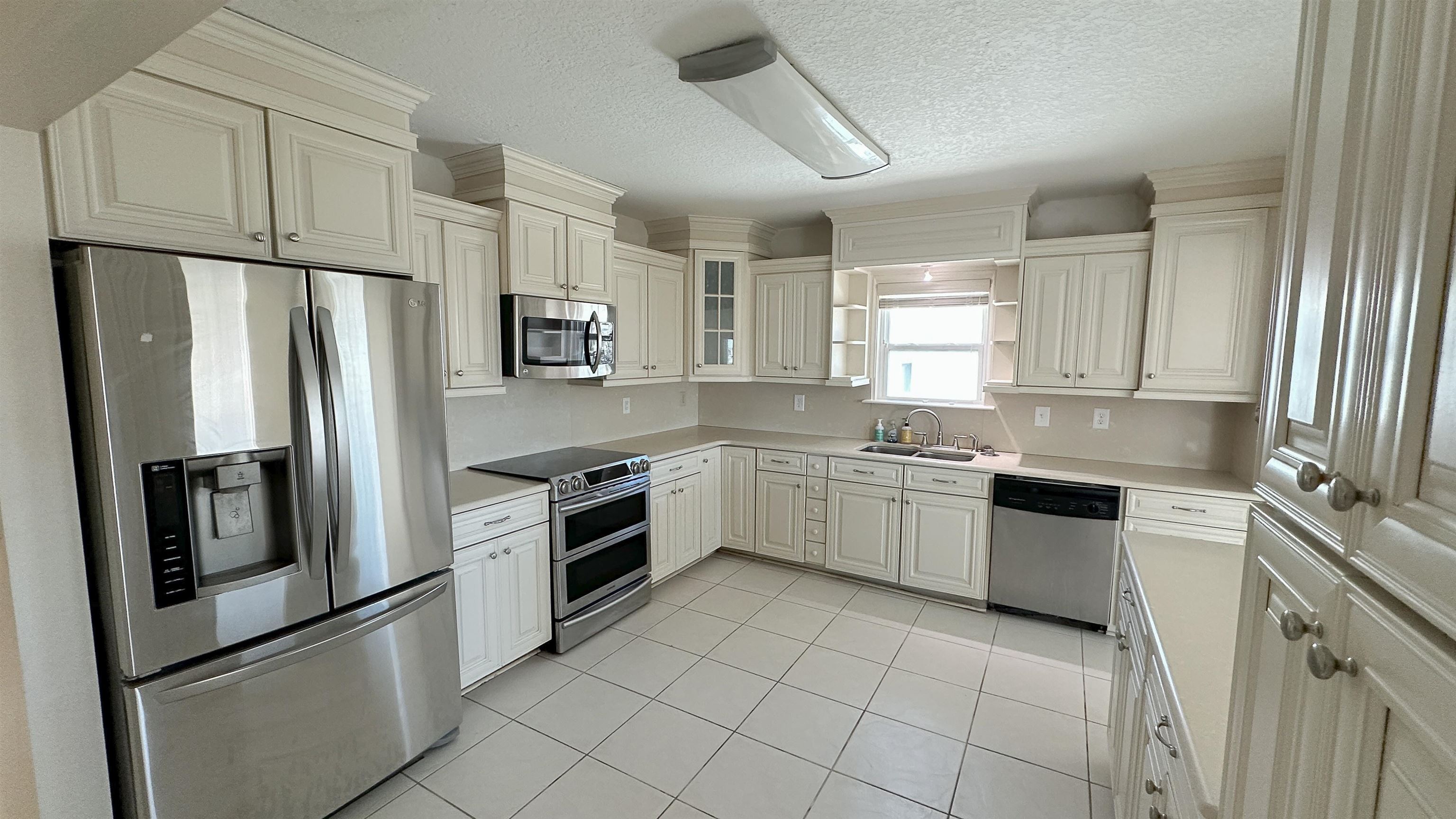 2 11th Street St. Augustine Beach, FL 32080 - Photo 55 of 72 Kitchen with stainless steel appliances, light countertops, a textured ceiling, glass insert cabinets, and white cabinets