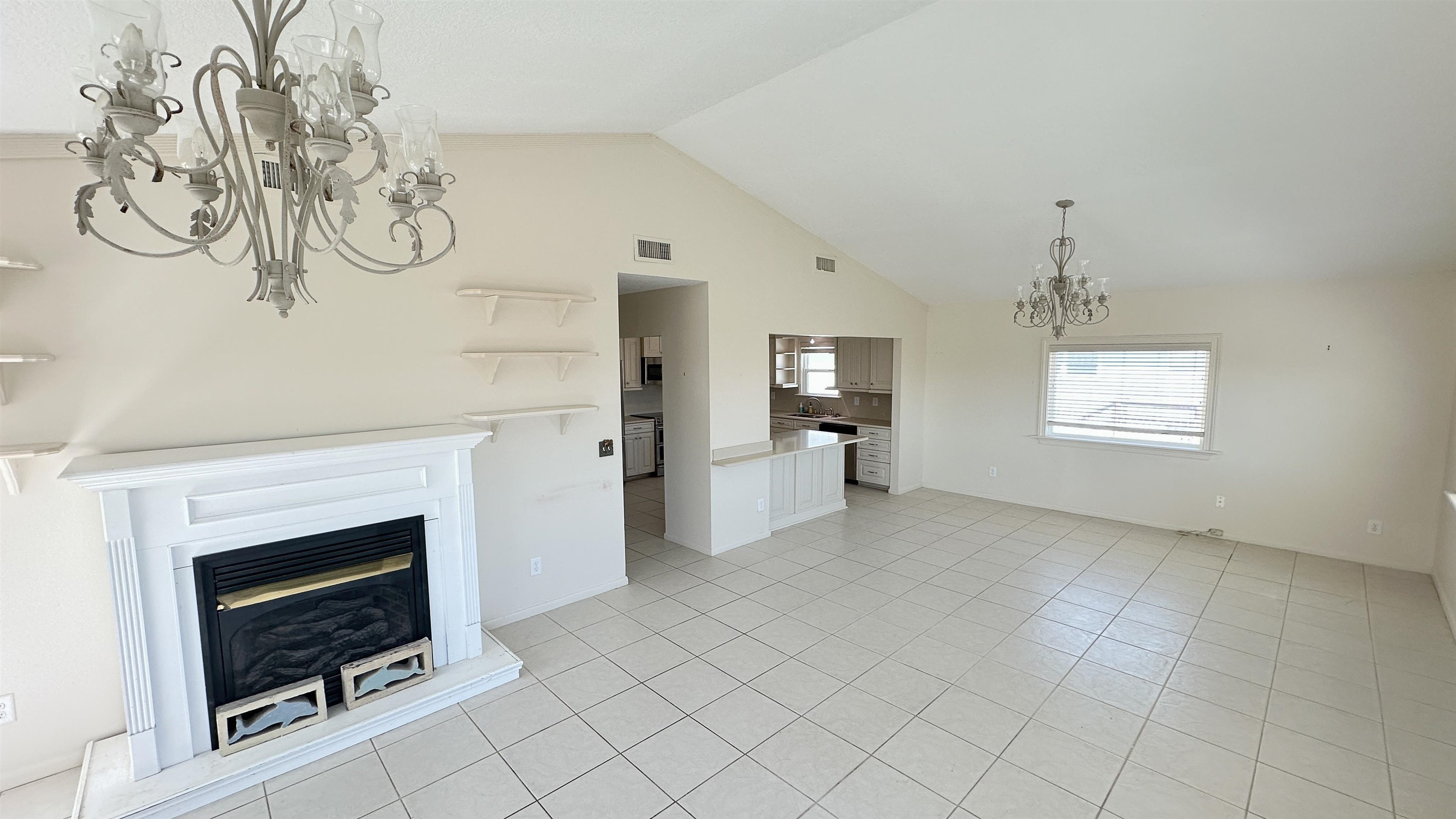 2 11th Street St. Augustine Beach, FL 32080 - Photo 58 of 72 Unfurnished living room featuring suspended lighting, light tile patterned floors, a high ceiling, and a glass covered fireplace