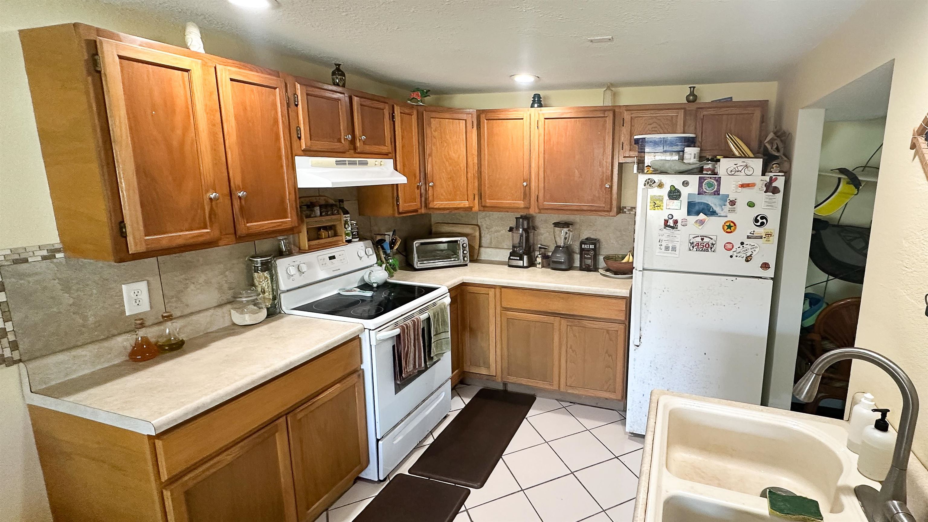 2 11th Street St. Augustine Beach, FL 32080 - Photo 64 of 72 Downstaris Kitchen featuring white appliances, wood finish cabinetry, light countertops, light tile patterned flooring, and a textured ceiling