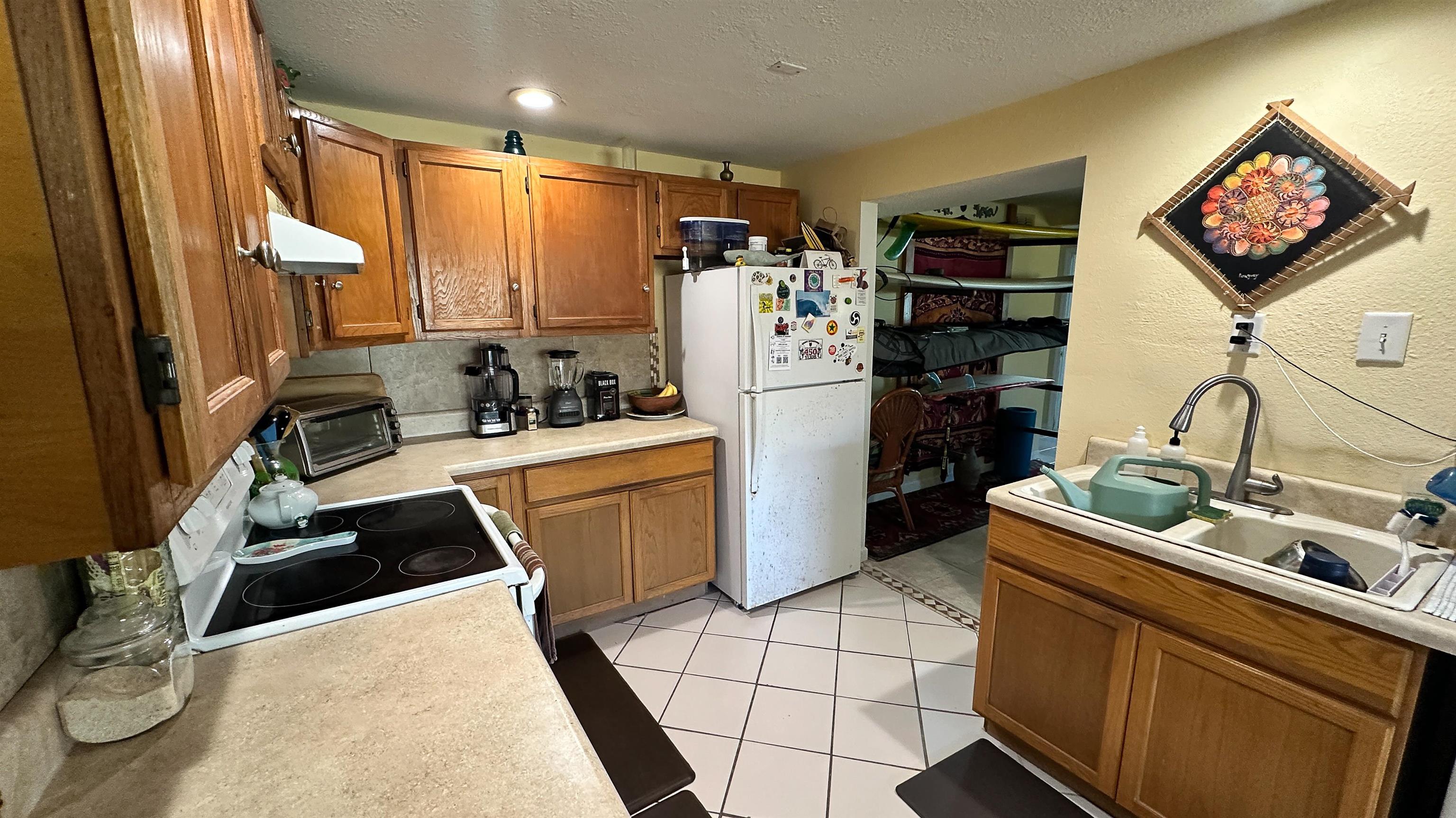 2 11th Street St. Augustine Beach, FL 32080 - Photo 65 of 72 Kitchen featuring wood finish cabinetry, a textured wall, range with electric stovetop, freestanding refrigerator, and light countertops