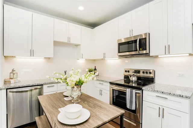 a kitchen with stainless steel appliances kitchen island granite countertop a sink a stove a microwave cabinets and a refrigerator