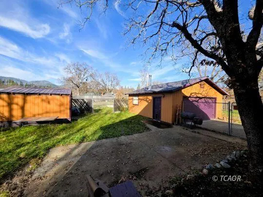 a view of a big yard with table and chairs a fire pit and a large tree