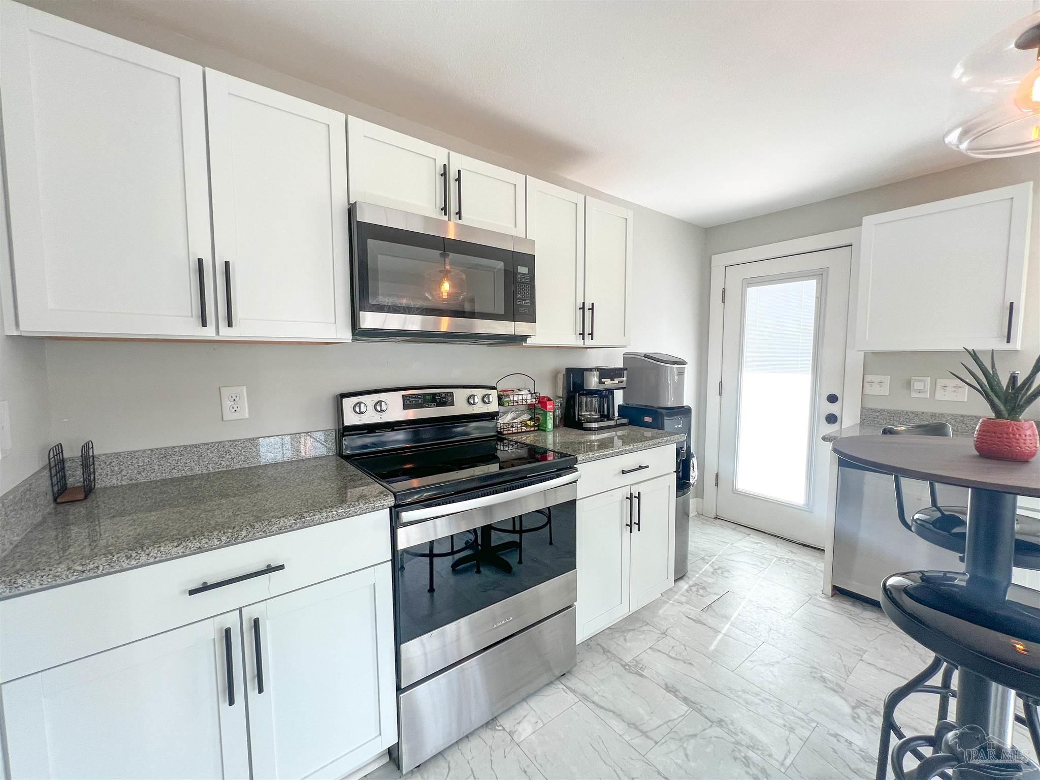 1315 Dexter Avenue Pensacola, FL 32507 - Photo 6 of 22 a kitchen with stainless steel appliances granite countertop a stove a sink and a microwave