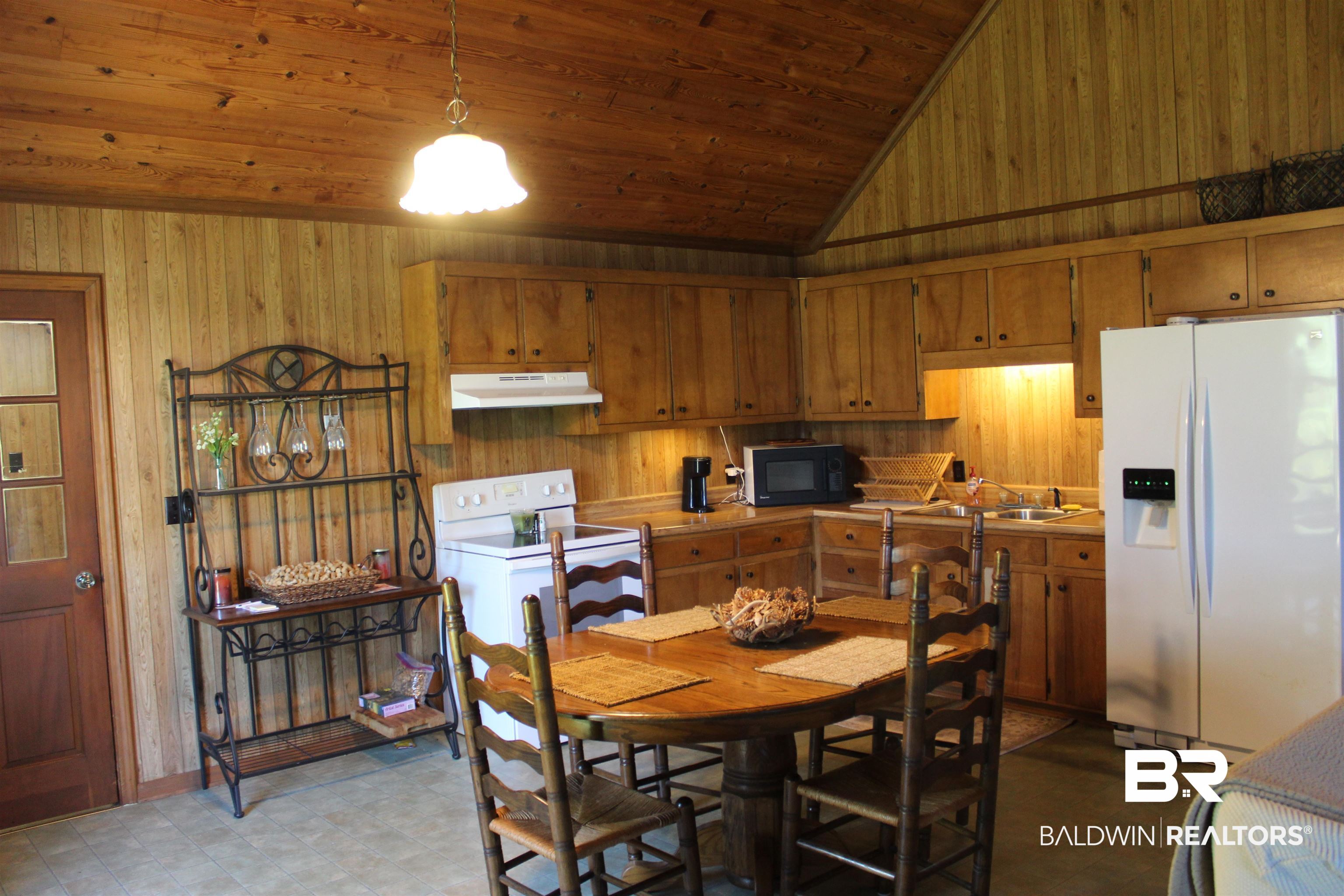 6447 Henderson Road Lowndesboro, AL 36752 - Photo 10 of 22 Dining area with wood walls, dark flooring, and a vaulted wood ceiling