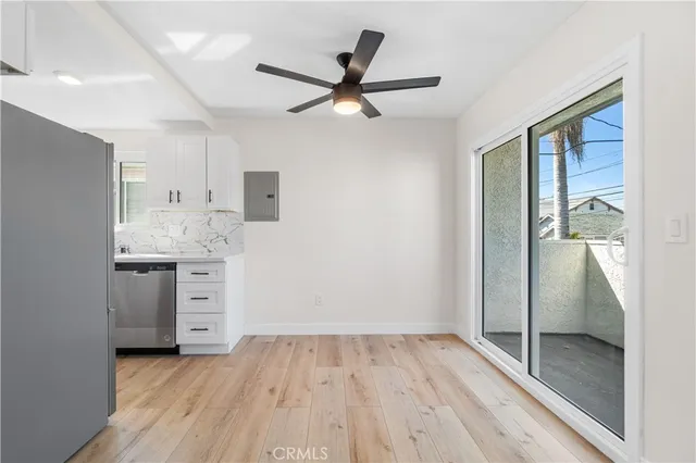 a view of a hallway to a bedroom with wooden floor and a ceiling fan