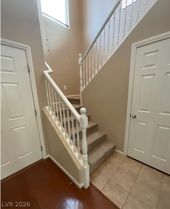 10841 Paradise Road Henderson, NV 89052 - Photo 10 of 35 A grand staircase with white spindles gracefully ascends, illuminated by natural light from a high window.