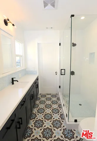 a bathroom with a double vanity sink a toilet and shower