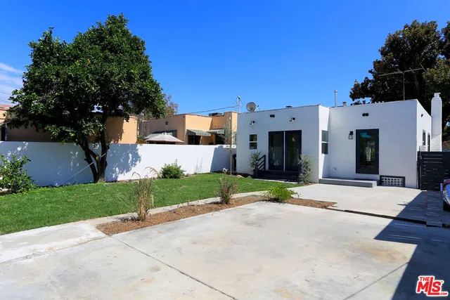 a view of a house with a yard and large tree