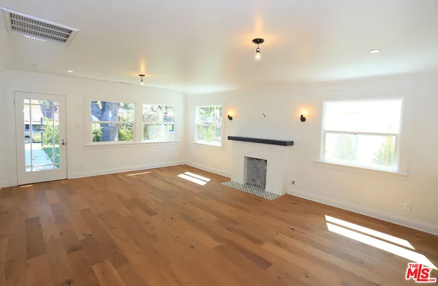an empty room with windows and fireplace