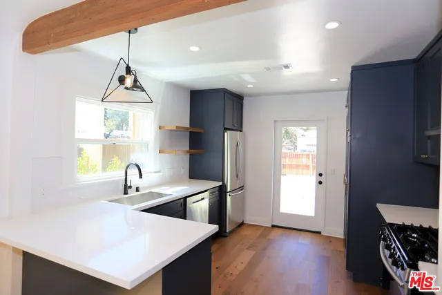 a kitchen with stainless steel appliances a sink a window and wooden floor