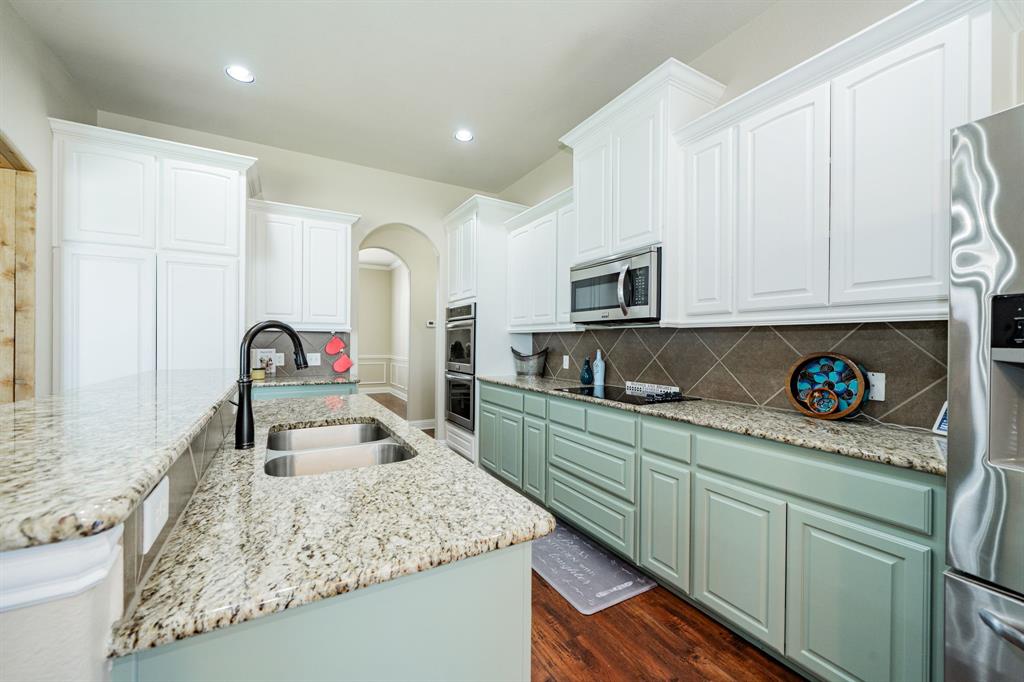 14176 Paterson Road Talty, TX 75126 - Photo 12 of 40 a kitchen with stainless steel appliances granite countertop a sink a stove and a microwave