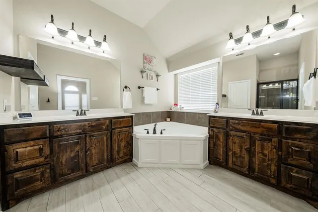 a spacious bathroom with a double vanity sink mirror and bathtub