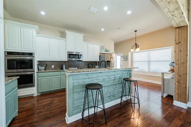 a kitchen with kitchen island granite countertop wooden floors and white stainless steel appliances