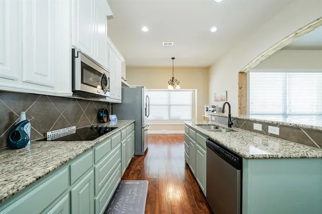 a kitchen with granite countertop a sink a counter top space appliances and cabinets