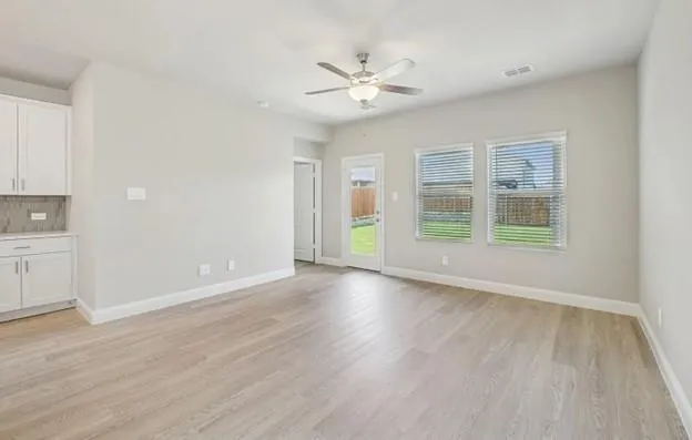 a view of an empty room with a window and wooden floor