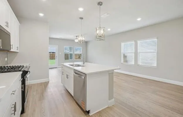 a kitchen with a stove a sink a refrigerator and wooden floor