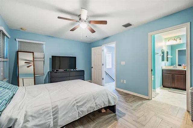 a bedroom with a large bed a flat tv screen and a chandelier
