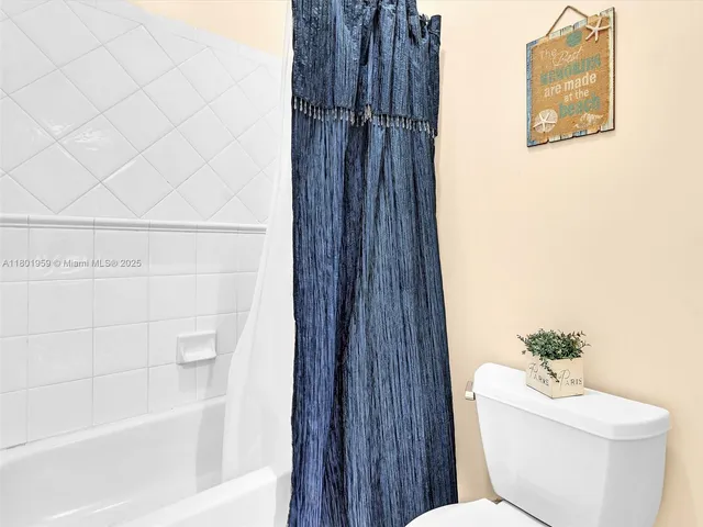 a bath room with a granite countertop toilet a sink and a large mirror