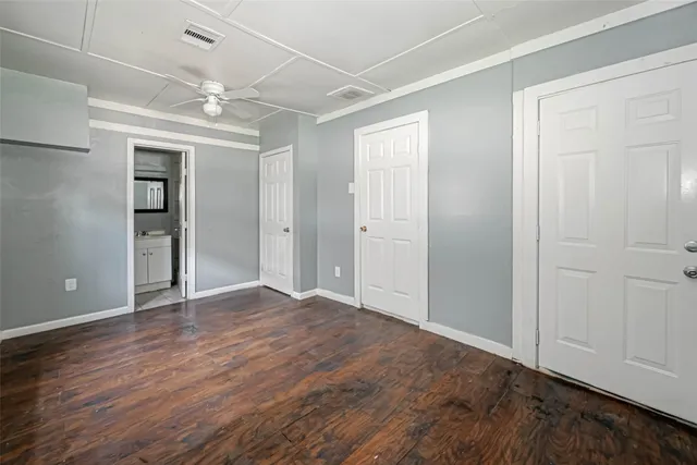 an empty room with wooden floor closet and windows