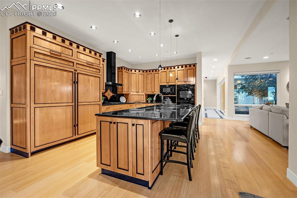 205 Cobblestone Way Monument, CO 80132 - Photo 12 of 45 a kitchen with stainless steel appliances granite countertop a stove a refrigerator a sink a dining table and chairs with wooden floor