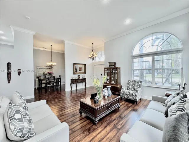 a living room with furniture large window and wooden floor