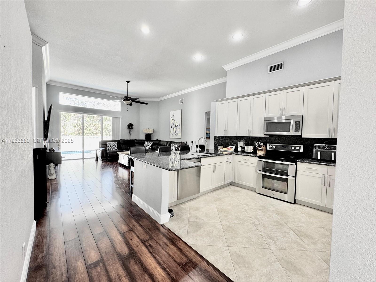 19754 Dinner Key Drive Boca Raton, FL 33498 - Photo 9 of 48 a white kitchen with wooden floor and black appliances