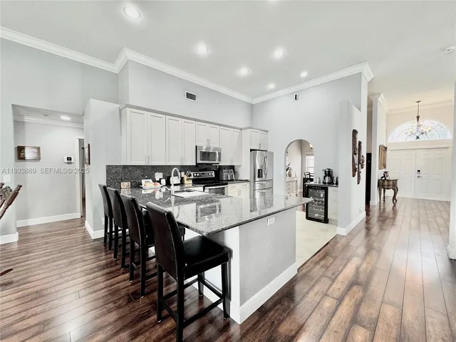 a kitchen with stainless steel appliances a dining table chairs and wooden floor