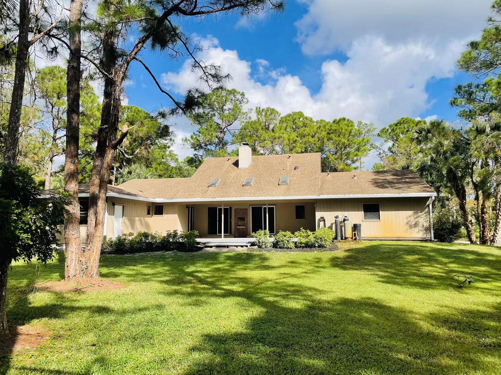 9296 166th Way North Jupiter, FL 33478 - Photo 25 of 31 a front view of a house with garden and trees