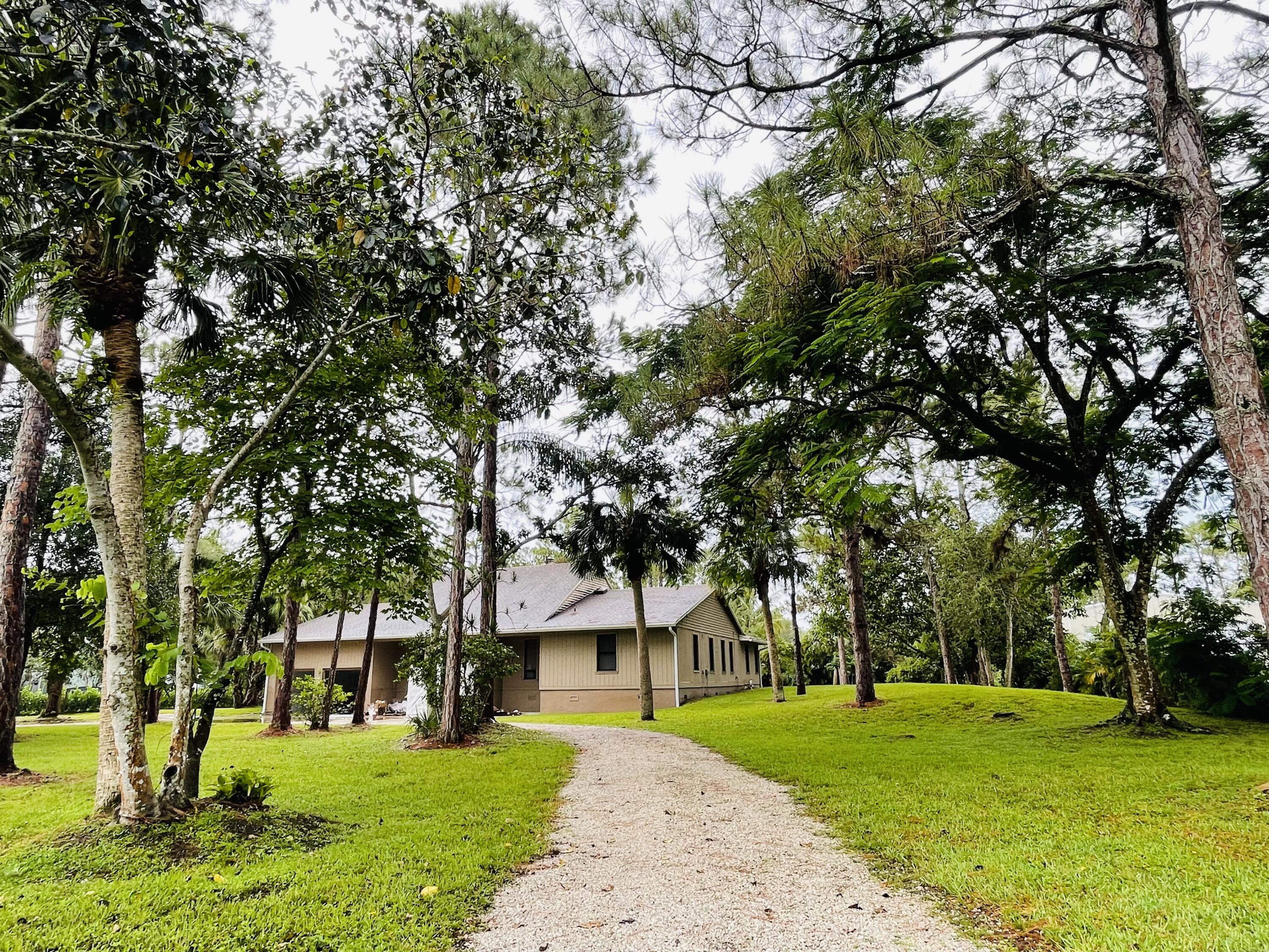 9296 166th Way North Jupiter, FL 33478 - Photo 29 of 31 a view of a big house with a big yard and large trees