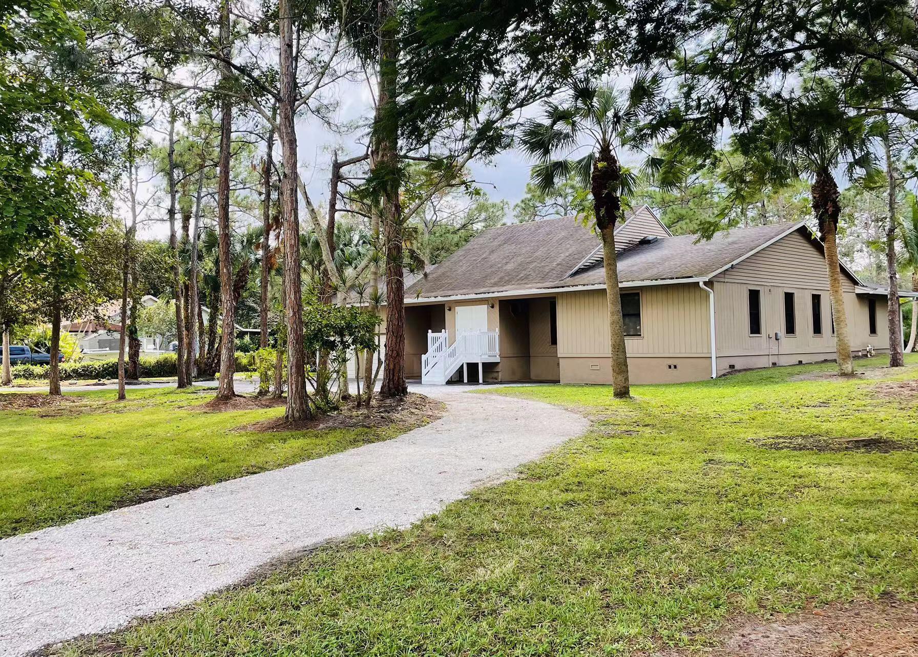 9296 166th Way North Jupiter, FL 33478 - Photo 3 of 31 a front view of a house with a garden and trees