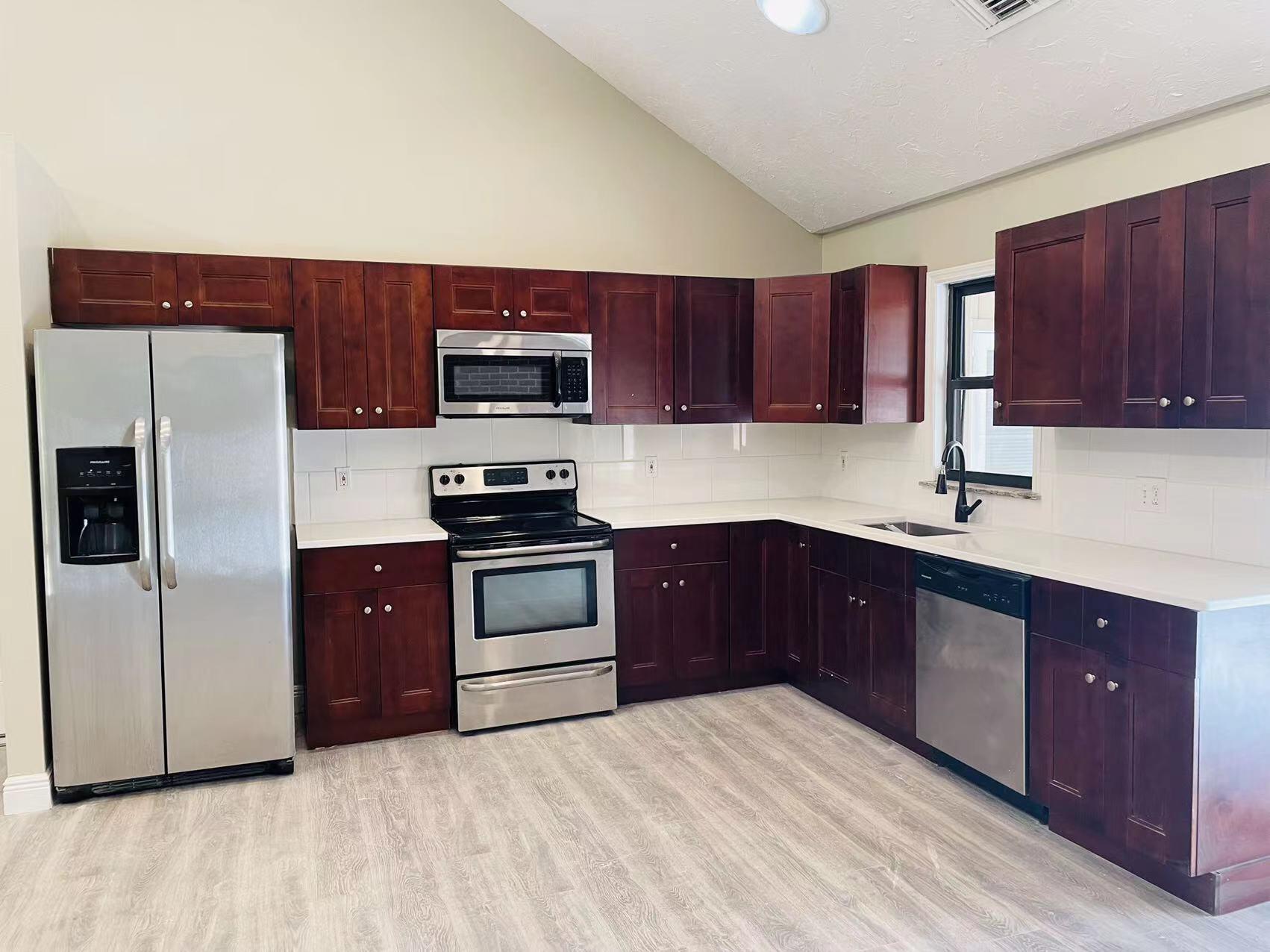 9296 166th Way North Jupiter, FL 33478 - Photo 7 of 31 a kitchen with a sink a microwave a refrigerator and cabinets
